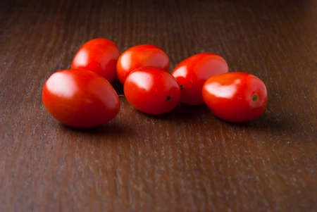 Six red fresh Cherry tomatoes on a wood tableの写真素材