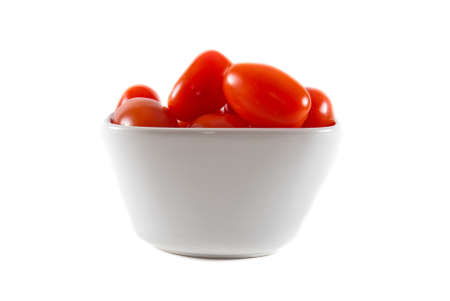 A white bowl of fresh red cherry tomatoes on a white isolated background.の写真素材