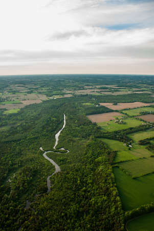 Aerial of a winding river surrounded by forest and agriculture