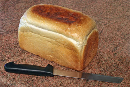 a loaf of freshly baked bread and a knife on a granite worktopの写真素材