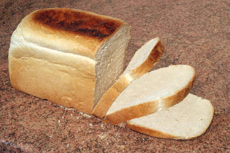 a loaf of freshly baked bread with some slices cut, on a granite worktopの写真素材
