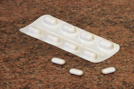 a blister pack of tablets and three loose tabletsの写真素材