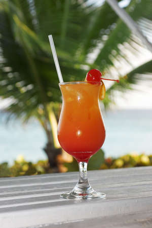a tequila sunrise waiting to be drunk with a de-focused palm tree in the background, taken in Barbadosの写真素材