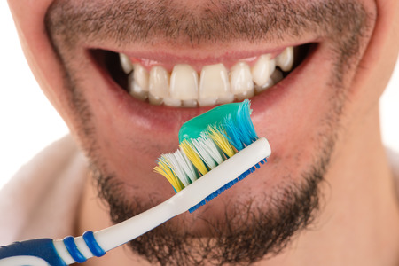 lower part of face of man with beard and mustache and white and blue toothbrush and white towel, closeupの写真素材