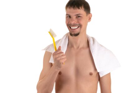 smiling adult naked man with big bright yellow toothbrush in hand and white towel on his shoulders looking at cameraの写真素材