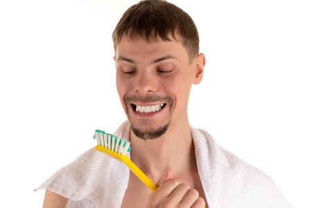 portrait of a man smiling broadly looking at a giant white toothbrush with toothpaste in his handの写真素材