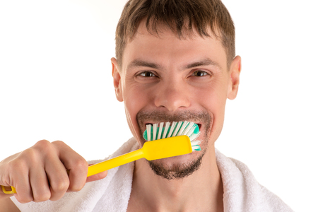 portrait of adult smiling man with big yellow toothbrush in hand and white towel on his shouldersの写真素材