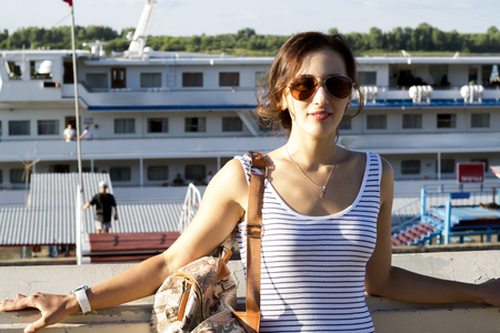 Beautiful girl with a bag on his shoulder against the background of a cruise shipの写真素材