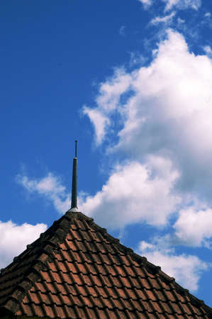 Old roof and tiles and white clouds on blue skyの写真素材