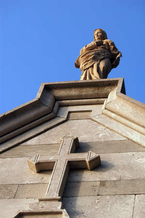 Statue and stone cross on the church wallの写真素材