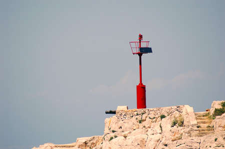New red lightgouse on the rocks near seaの写真素材