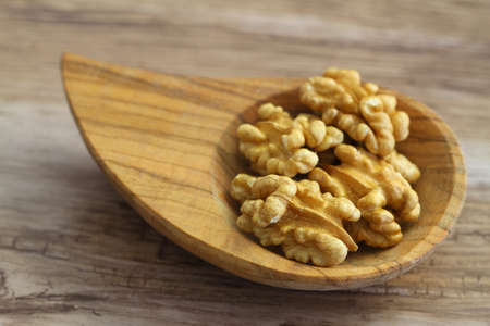 Walnuts without shell in vintage bowl on wooden background, close up