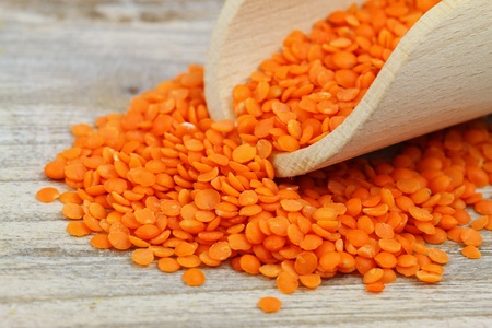 Dry red lentils in wooden scoop, close upの写真素材