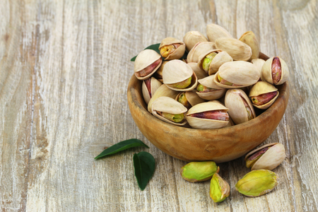 Pistachios with and without shell in wooden bowl with copy spaceの写真素材
