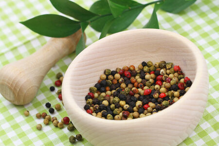 Mortar and pestle with mixed peppers on green checkered clothの写真素材