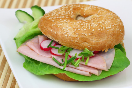 Bagel with ham, lettuce, cucumber and radish, close upの写真素材