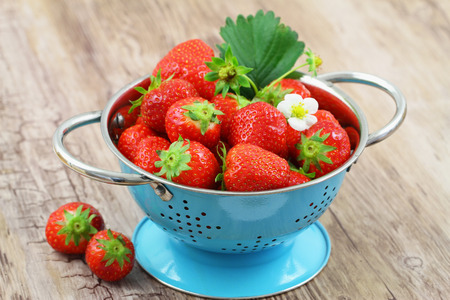 Fresh strawberries in blue colanderの写真素材
