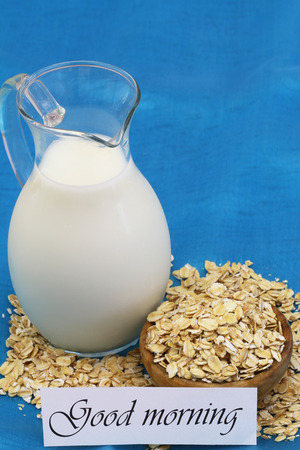 Good morning card with oatmeal and jug of milk on blue background with copy spaceの写真素材