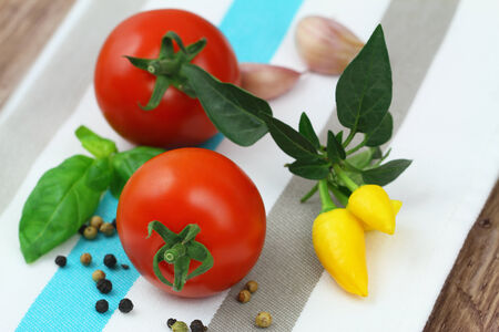 Cherry tomatoes with selection of fresh herbs and mixed peppersの写真素材