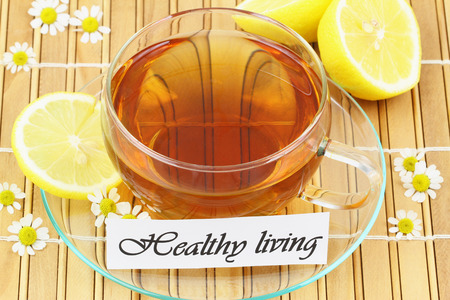 Healthy living card with cup of tea, chamomile flowers and lemonの写真素材