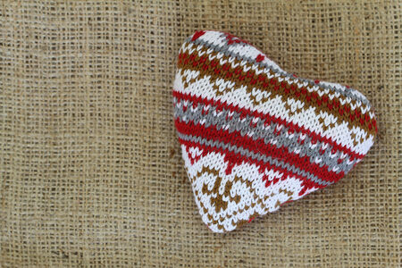 Knitted heart on jute background with copy spaceの写真素材