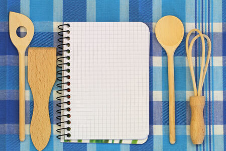 Notebook and wooden cooking utensils on blue and white checkered tableclothの写真素材