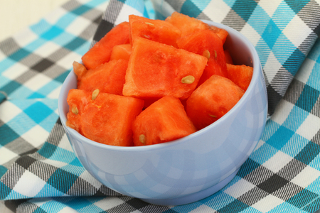 Watermelon cubes in blue bowl on checkered clothの写真素材