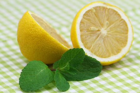 Lemon halves and fresh mint leaves on checkered clothの写真素材