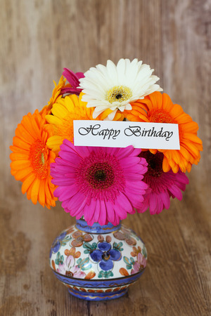 Happy Birthday card and colorful bouquet of gerbera daisies in vintage vaseの写真素材