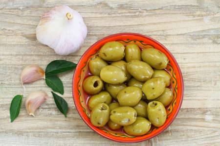 Green olives with garlic on wooden surfaceの写真素材