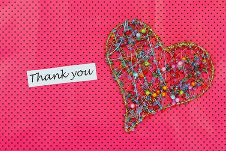Thank you card with heart made of beads on pink backgroundの写真素材
