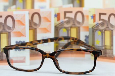 Reading glasses with banknotes in the backgroundの写真素材