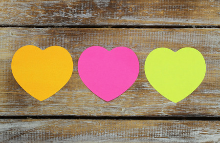 Three paper hearts on rustic wooden surface