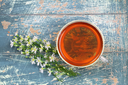 Tea and fresh chamomile flowers on rustic wood with copy spaceの写真素材