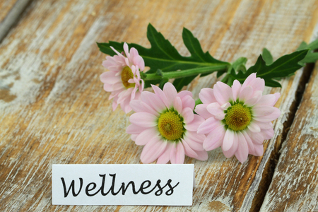 Wellness card with pink daisies on rustic wooden surfaceの写真素材