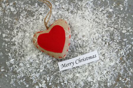 Merry Christmas card with red heart on canvas snowy surfaceの写真素材