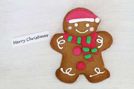 Merry Christmas card with gingerbread man on white wooden surface