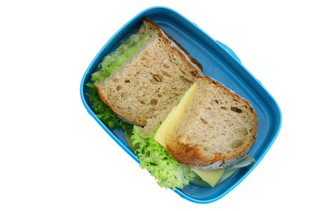 Lunch box containing rustic bread sandwiches with cheese and lettuce isolated on whiteの写真素材