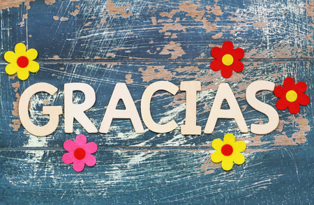 Gracias (thank you in Spanish) written with wooden letters on rustic surface and colorful flowersの写真素材