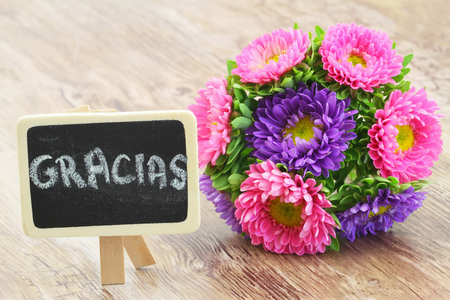 Gracias (thank you in Spanish) written on mini blackboard with colorful bouquet asterの写真素材