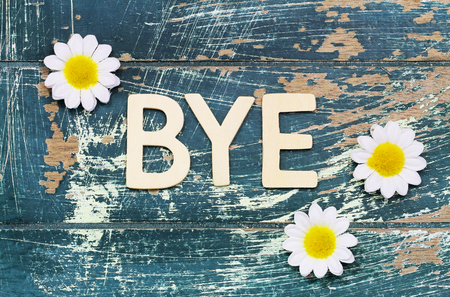 Word bye written with wooden letters on rustic surface and white daisiesの写真素材