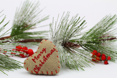 Merry Christmas written on canvas heart and pine covered with snow flakesの写真素材