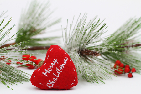 Merry Christmas written on red heart and pine covered with snow flakesの写真素材