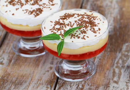 Traditional strawberry trifle dessert with fresh whipped cream and sprinkled with chocolate on rustic woodの写真素材