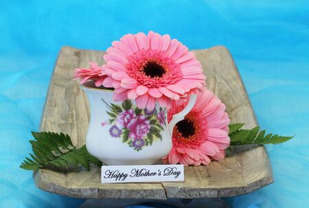 Happy Mother's Day card with pink gerbera daisies in vintage porcelain cupの写真素材