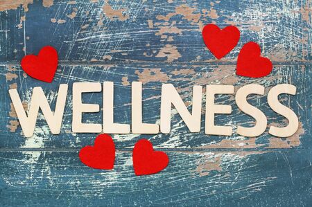 Wellness written with wooden letters on rustic surface with red heartsの写真素材
