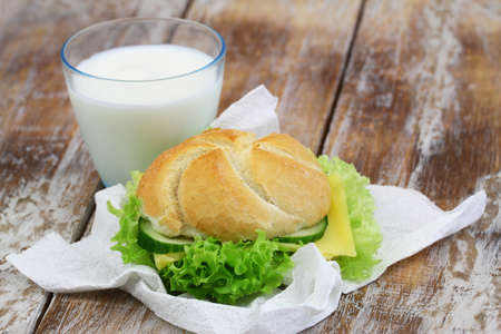 Simple lunch consisting of cheese roll with lettuce and glass of milkの写真素材