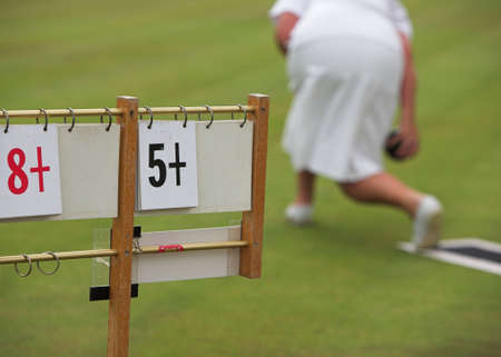 A lady playing lawn bowls and the scoreboard.の写真素材