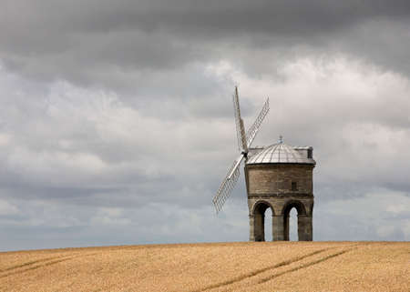 An old stone windmill standing in a cornfield.の写真素材