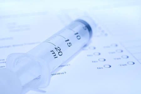 A syringe lying on a health questionnaire.の写真素材